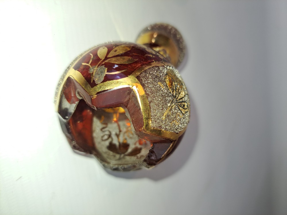 A pair of ruby red glass decorative bells featuring hand-painted gold foliage motifs and textured gilded bands. View II