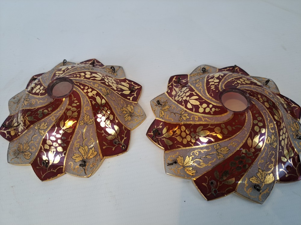A pair of scalloped Bohemian ruby glass bobeches with frosted panels, hand-painted gold leaf vine patterns, and small metal wire loops. View II