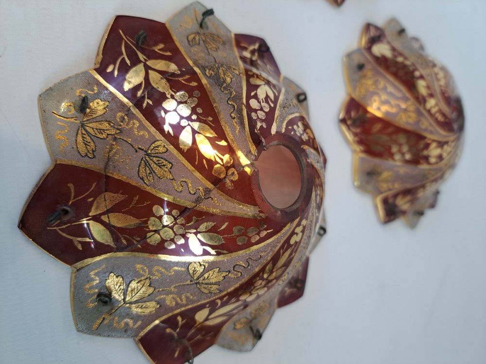 A pair of scalloped Bohemian ruby glass bobeches with frosted panels, hand-painted gold leaf vine patterns, and small metal wire loops. View VI