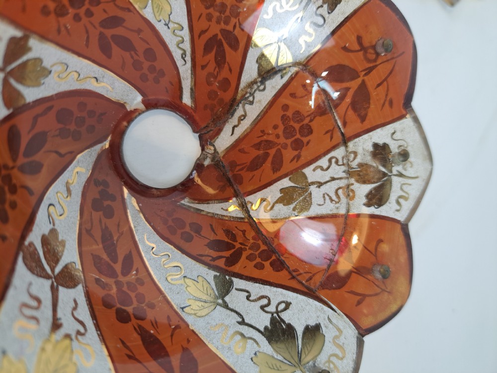 A pair of scalloped Bohemian ruby glass bobeches with frosted panels, hand-painted gold leaf vine patterns, and small metal wire loops. View VII