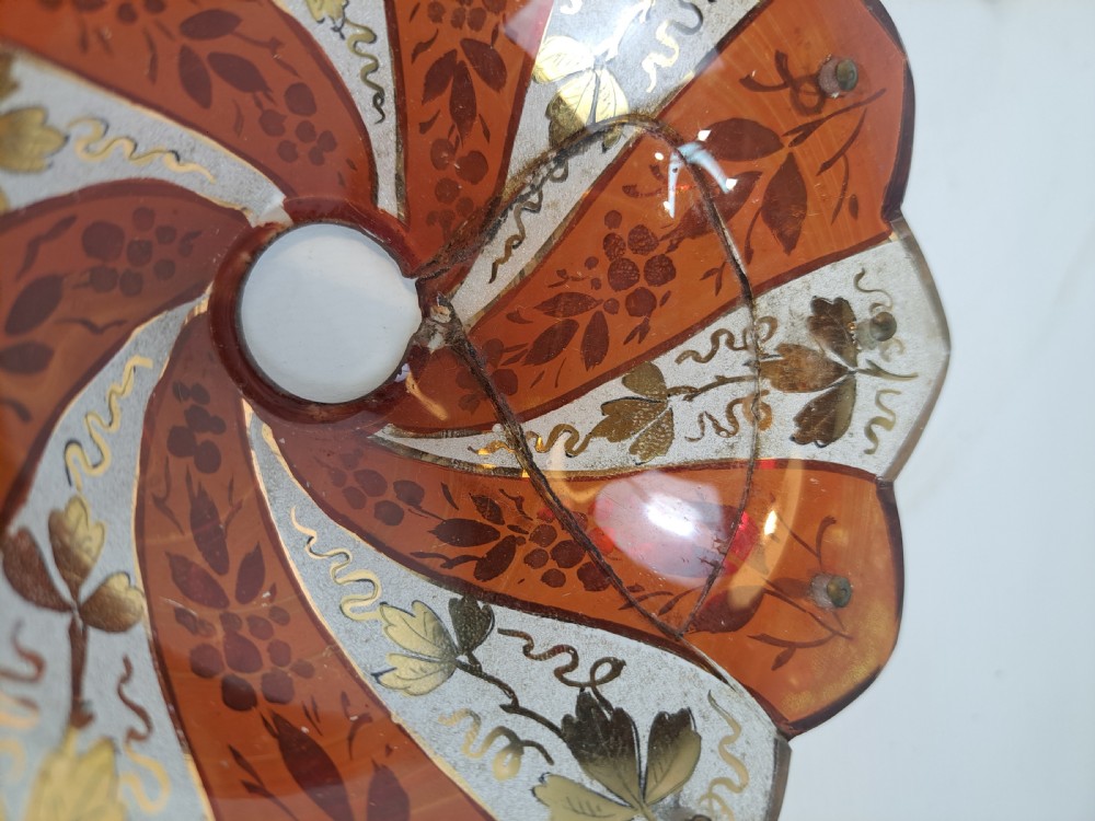 A pair of scalloped Bohemian ruby glass bobeches with frosted panels, hand-painted gold leaf vine patterns, and small metal wire loops. View VIII