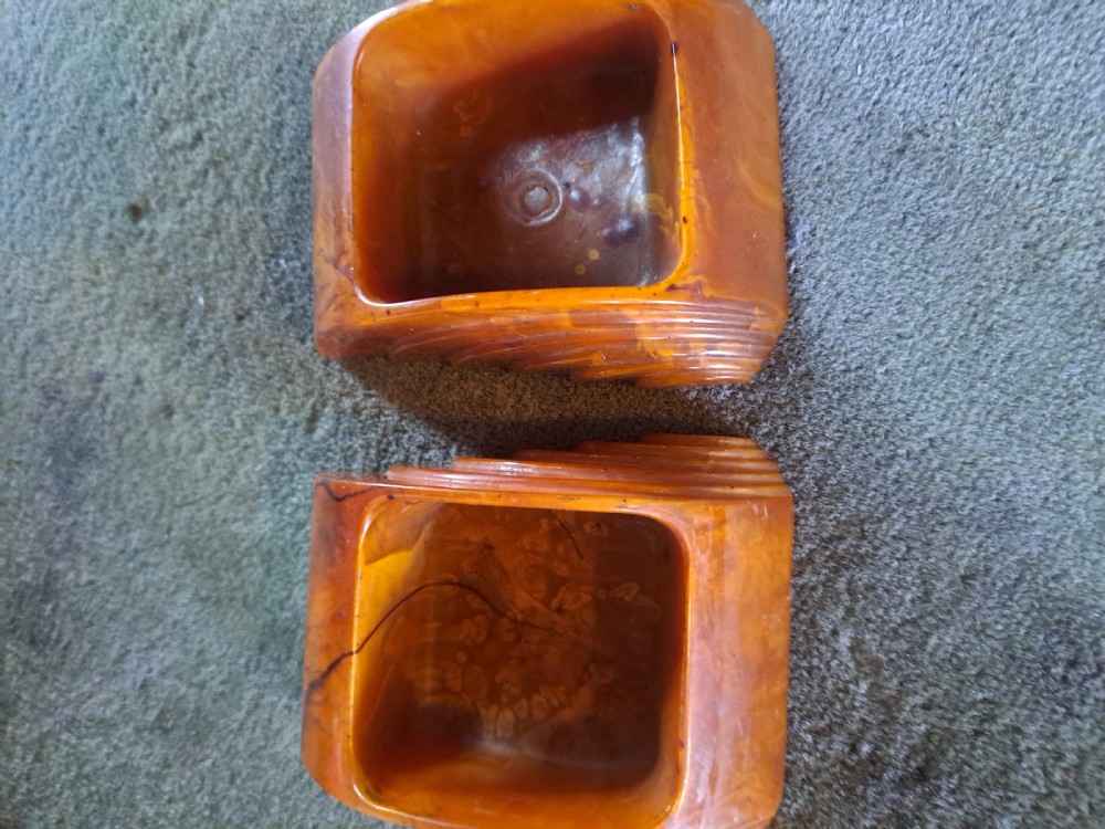 A pair of Art Deco amber phenolic resin stamp wetters featuring stepped side motifs and hollowed rectangular wells.
