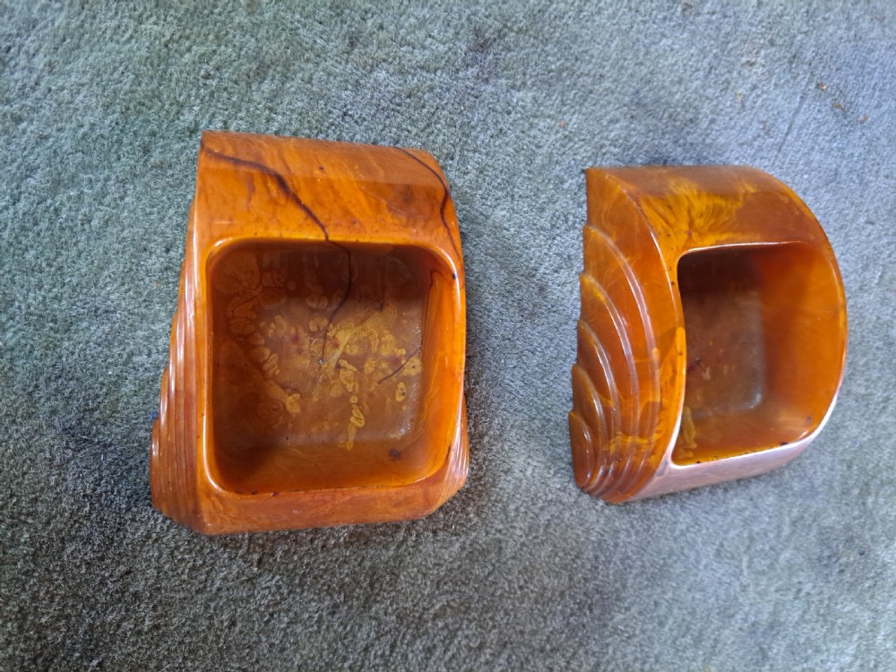 A pair of Art Deco amber phenolic resin stamp wetters featuring stepped side motifs and hollowed rectangular wells. View VI