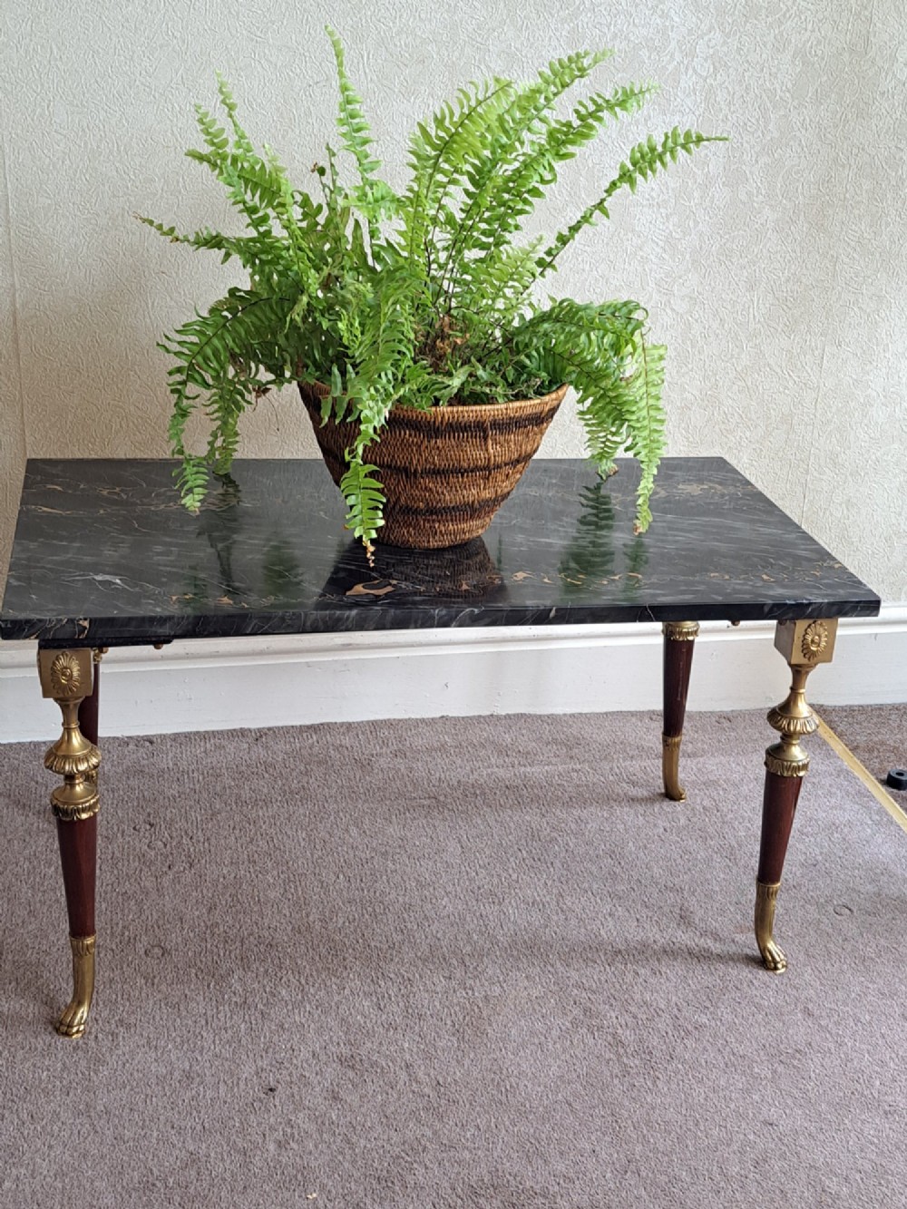 A rectangular coffee table featuring a dark veined marble top supported by tapered legs with ornamental brass mounts and brass feet.