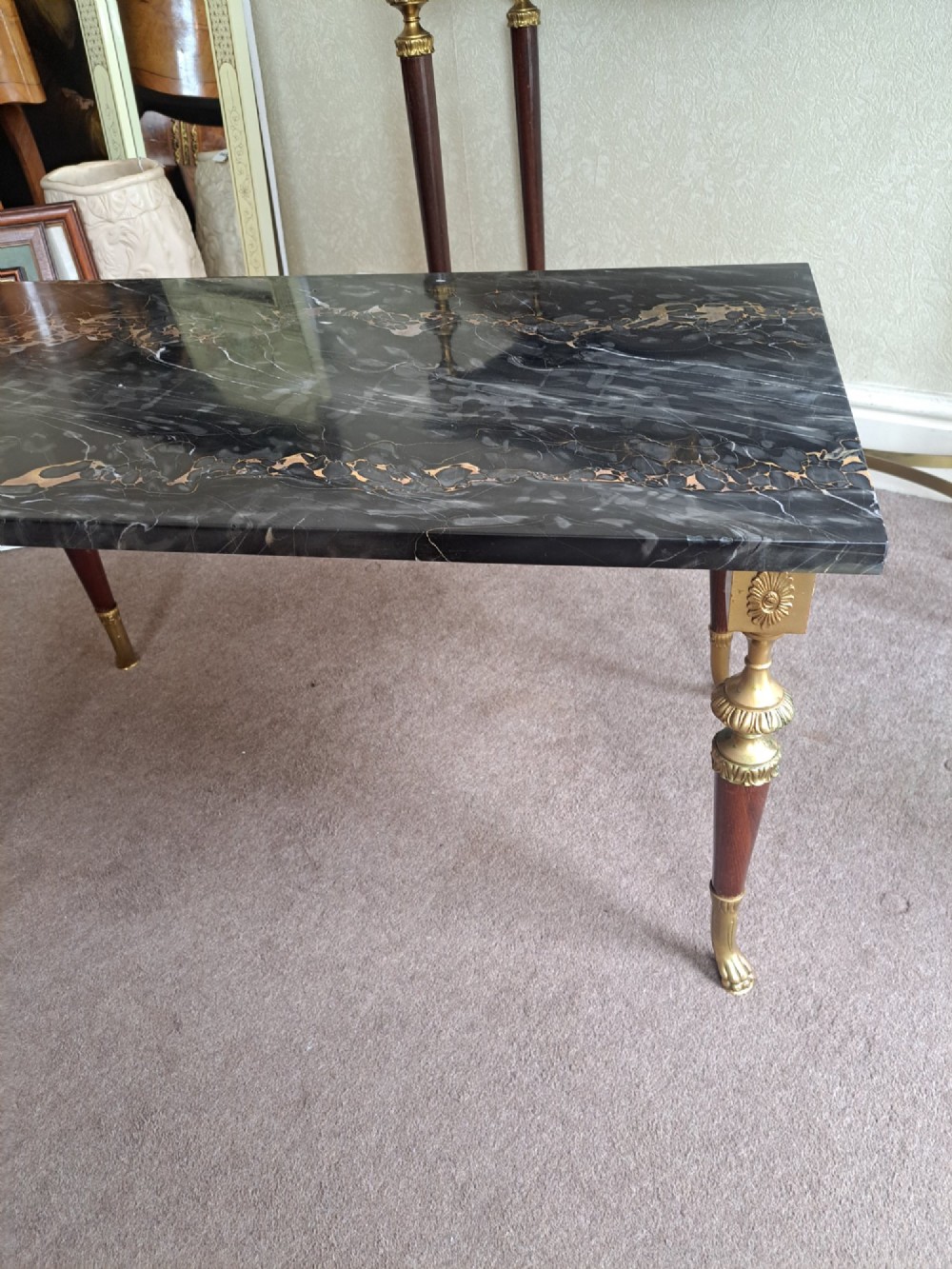 A rectangular coffee table featuring a dark veined marble top supported by tapered legs with ornamental brass mounts and brass feet. View X