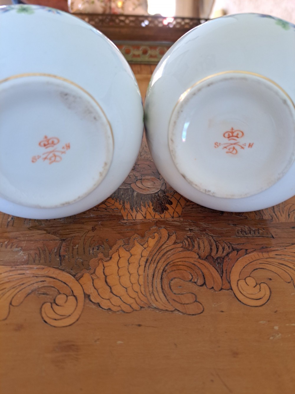 A pair of white porcelain bud vases featuring hand-painted floral motifs in pink, blue, and green with gilded rims and leaf accents. View III