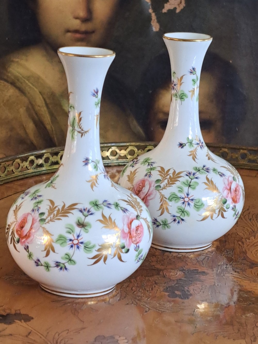 A pair of white porcelain bud vases featuring hand-painted floral motifs in pink, blue, and green with gilded rims and leaf accents. View VII