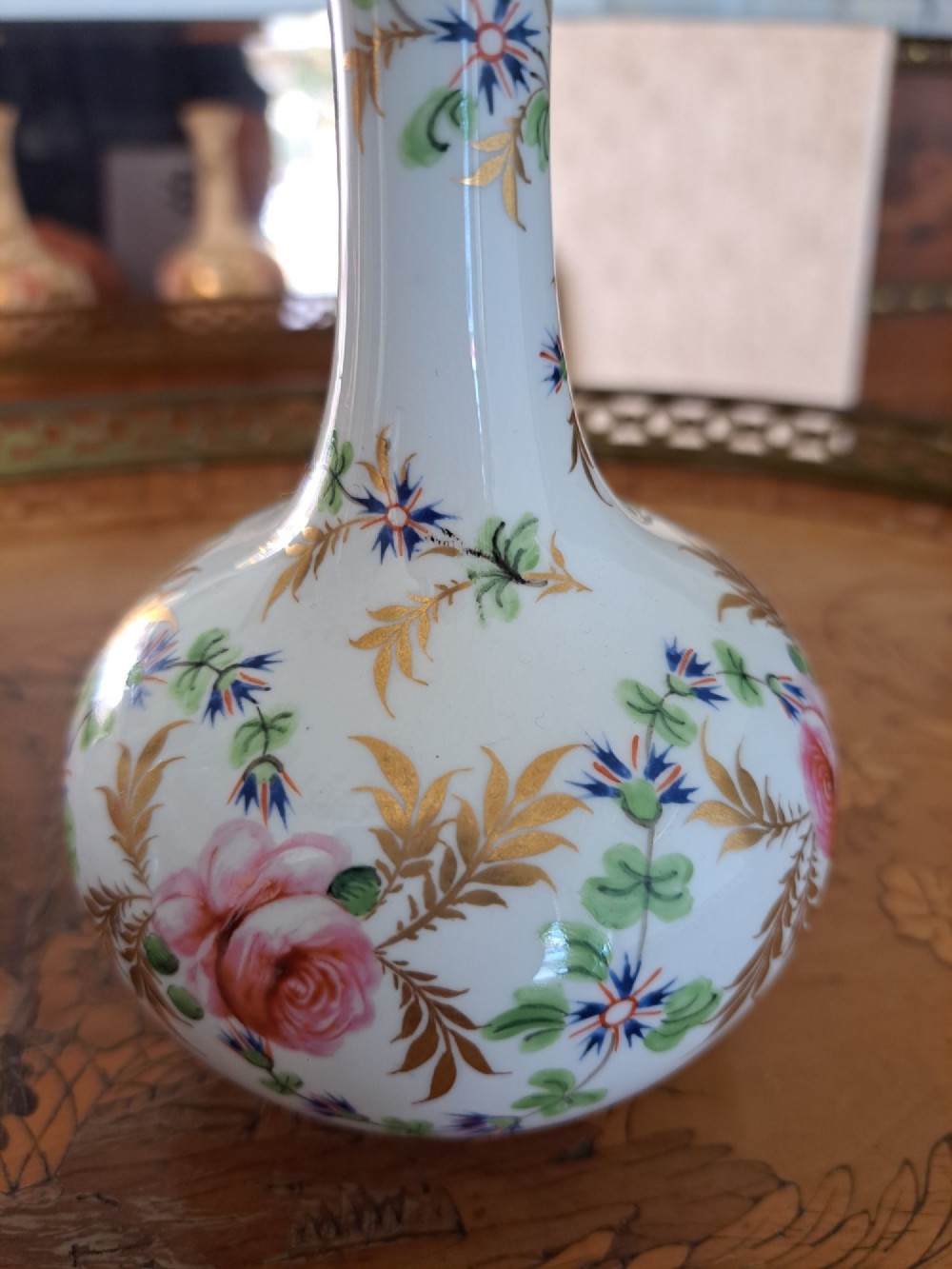 A pair of white porcelain bud vases featuring hand-painted floral motifs in pink, blue, and green with gilded rims and leaf accents. View IX