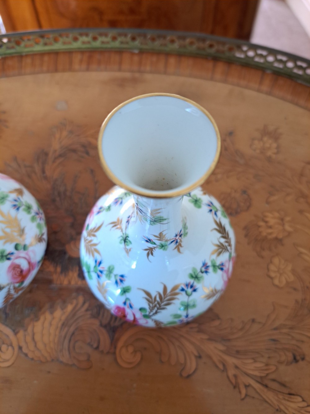 A pair of white porcelain bud vases featuring hand-painted floral motifs in pink, blue, and green with gilded rims and leaf accents. View XI