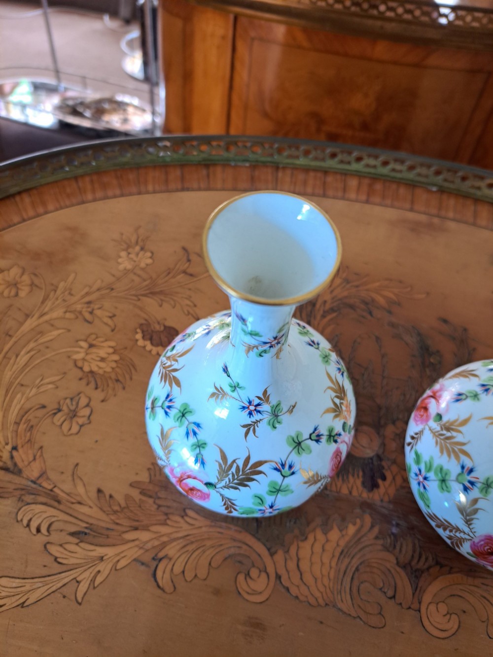 A pair of white porcelain bud vases featuring hand-painted floral motifs in pink, blue, and green with gilded rims and leaf accents. View XII