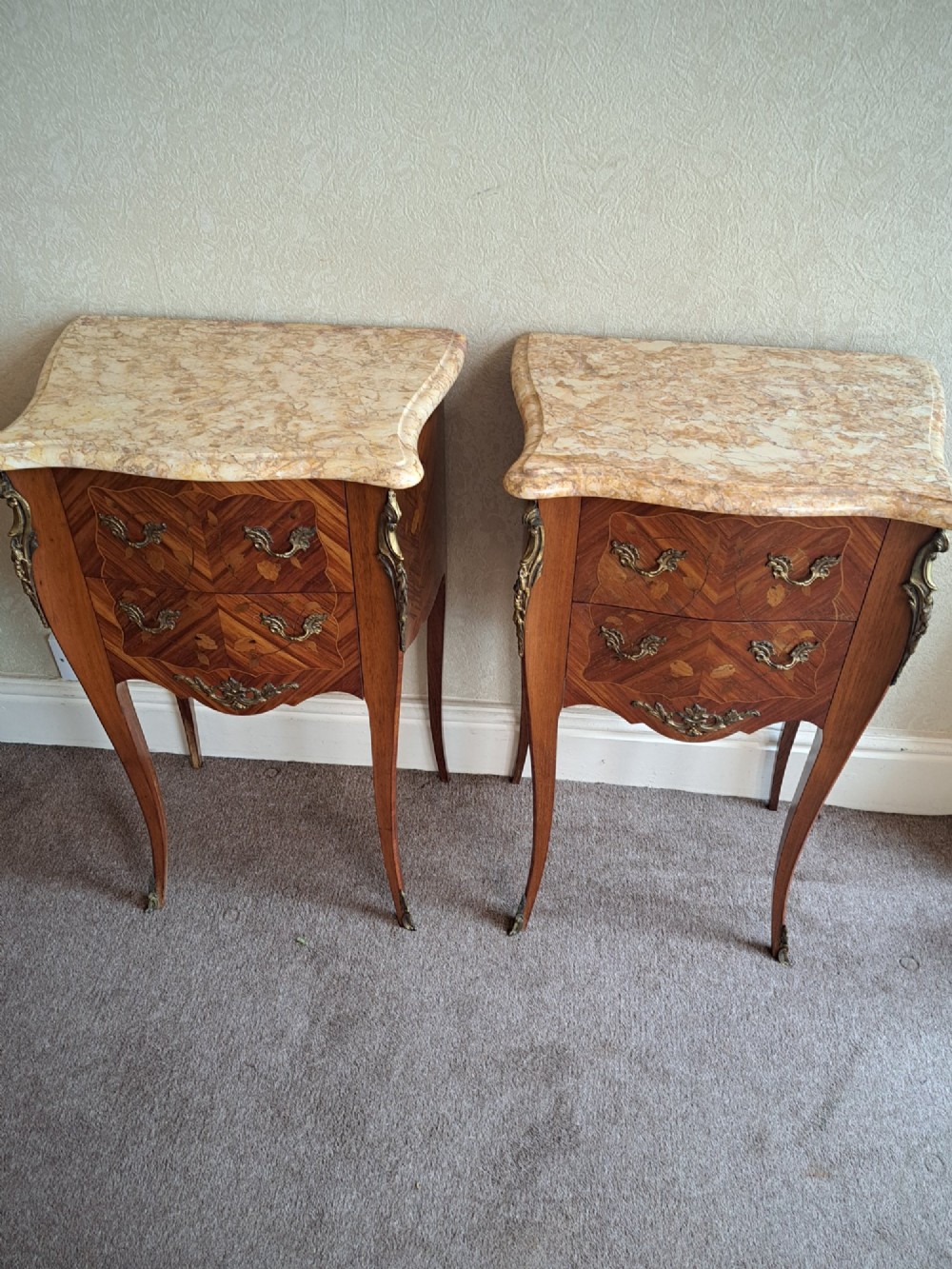 A pair of French style bedside tables featuring contoured beige marble tops, floral marquetry veneer drawers, brass handles, and sweeping cabriole legs. View II