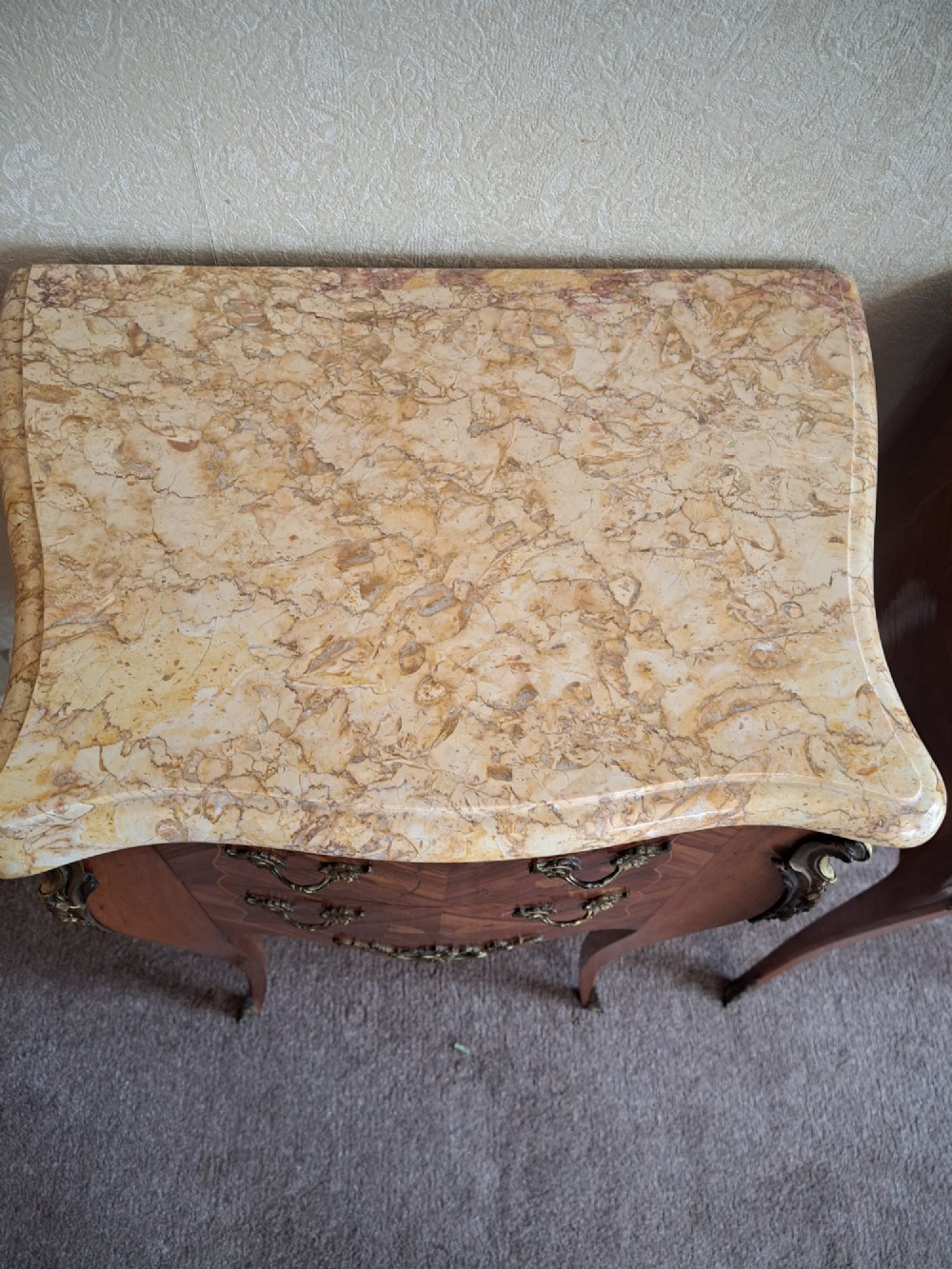 A pair of French style bedside tables featuring contoured beige marble tops, floral marquetry veneer drawers, brass handles, and sweeping cabriole legs. View IX
