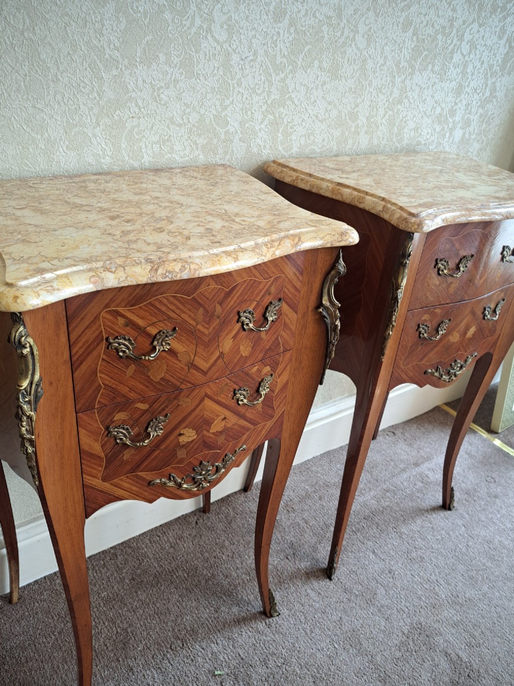 A pair of French style bedside tables featuring contoured beige marble tops, floral marquetry veneer drawers, brass handles, and sweeping cabriole legs. View XI