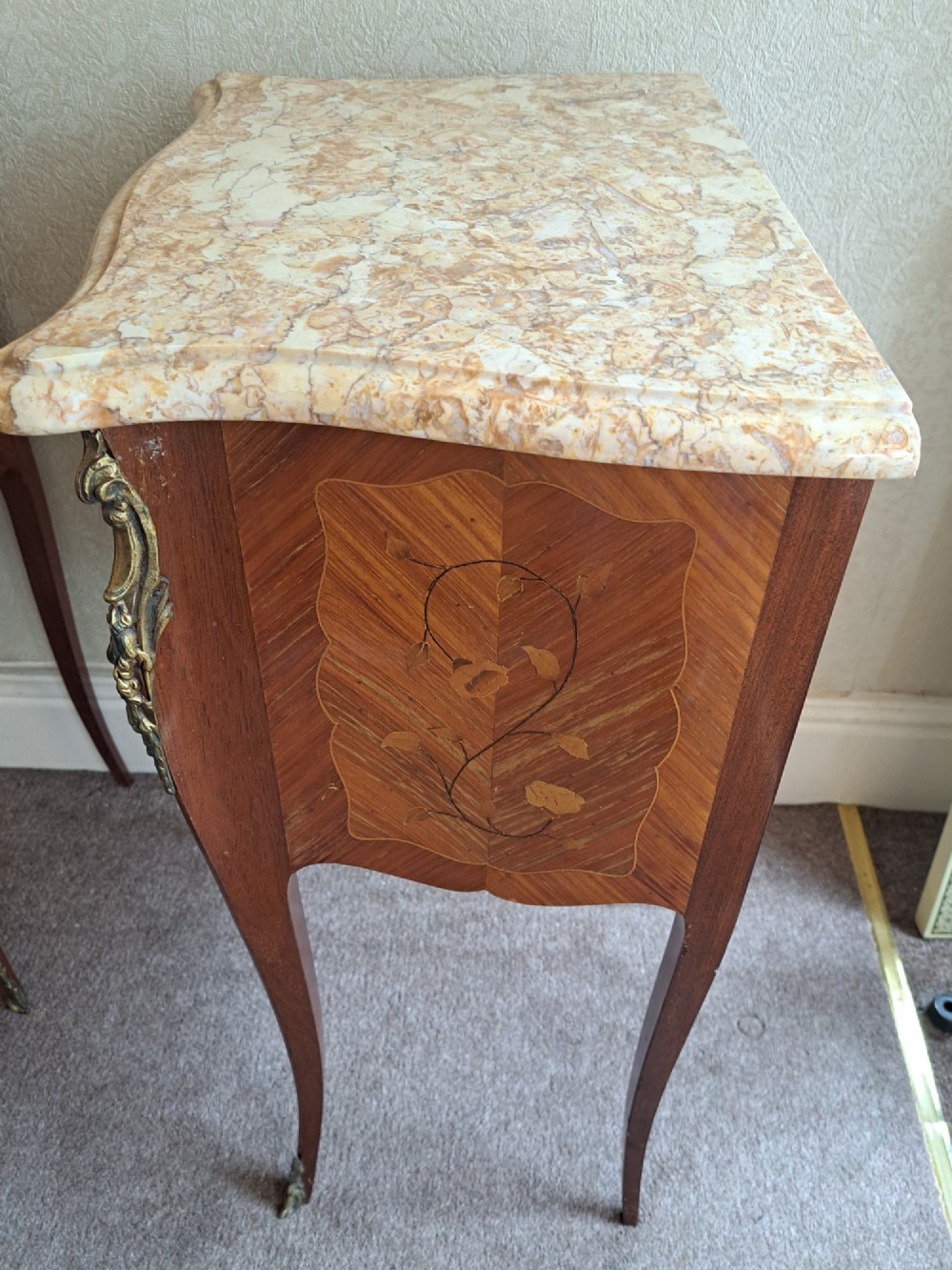 A pair of French style bedside tables featuring contoured beige marble tops, floral marquetry veneer drawers, brass handles, and sweeping cabriole legs. View XII