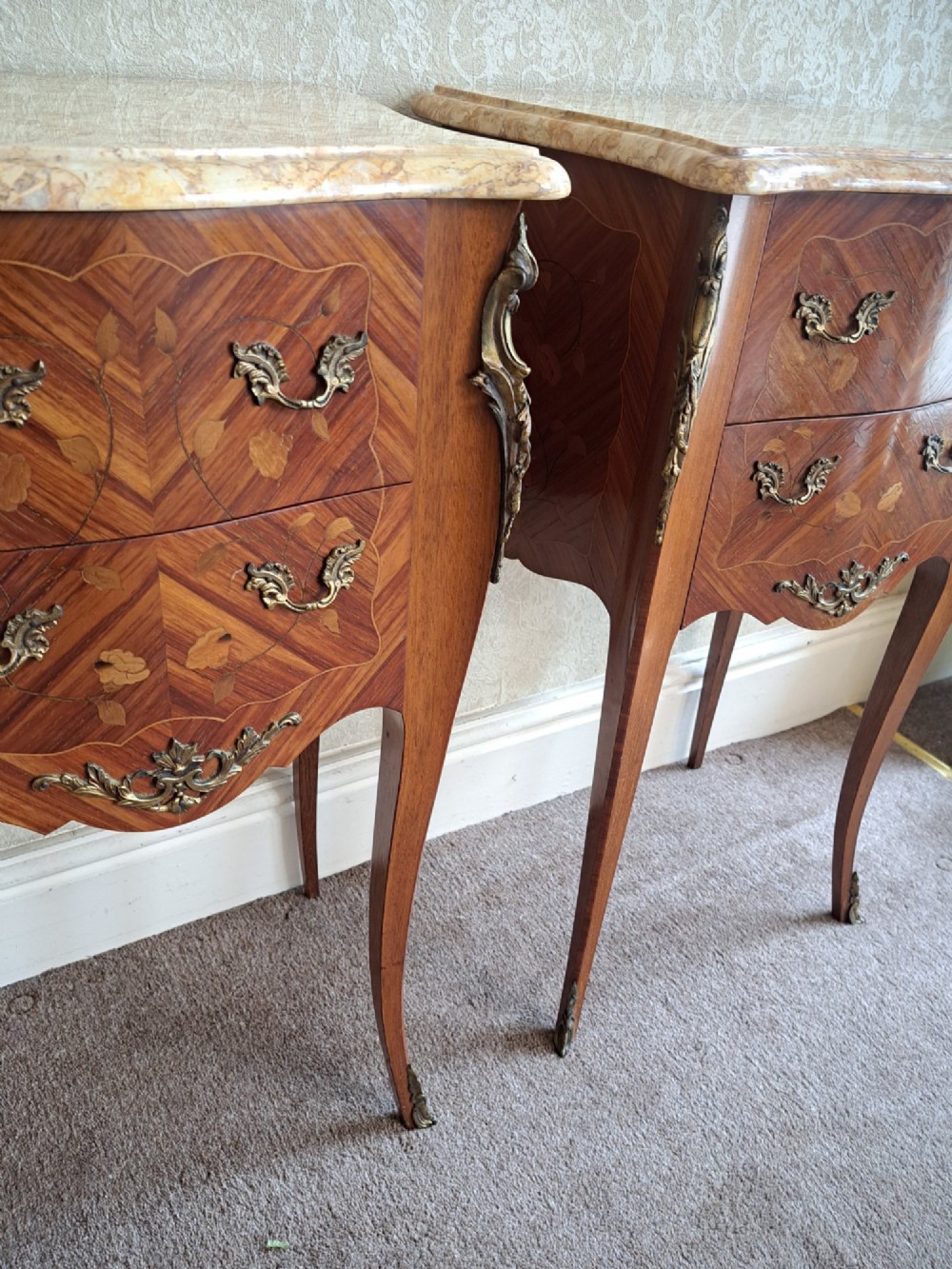 A pair of French style bedside tables featuring contoured beige marble tops, floral marquetry veneer drawers, brass handles, and sweeping cabriole legs. View XIII