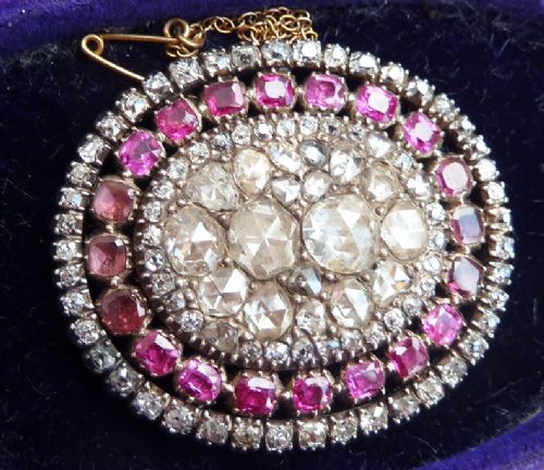 fig 1. An oval Georgian brooch featuring a central cluster of rose-cut diamonds surrounded by concentric rings of flat-cut pink rubies and small diamonds.