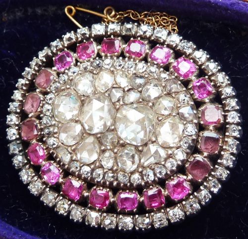 fig 2. An oval Georgian brooch featuring a central cluster of rose-cut diamonds surrounded by concentric rings of flat-cut pink rubies and small diamonds.