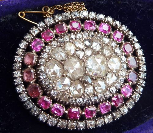 fig 3. An oval Georgian brooch featuring a central cluster of rose-cut diamonds surrounded by concentric rings of flat-cut pink rubies and small diamonds.