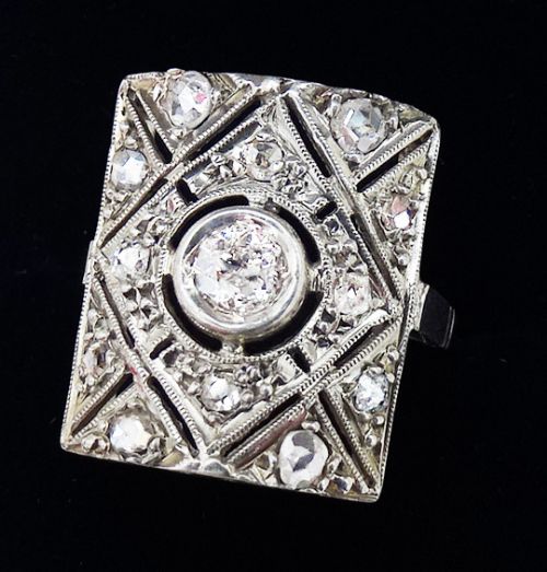 fig 1. An Art Deco rectangular platinum panel ring set with a central round diamond framed by milgrain detailing and geometric diamond accents.
