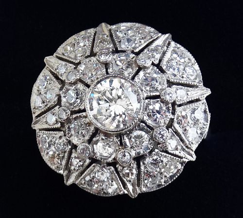 fig 1. An Art Deco platinum cluster ring featuring a circular starburst design set with round diamonds and decorated with fine millegrain edges.