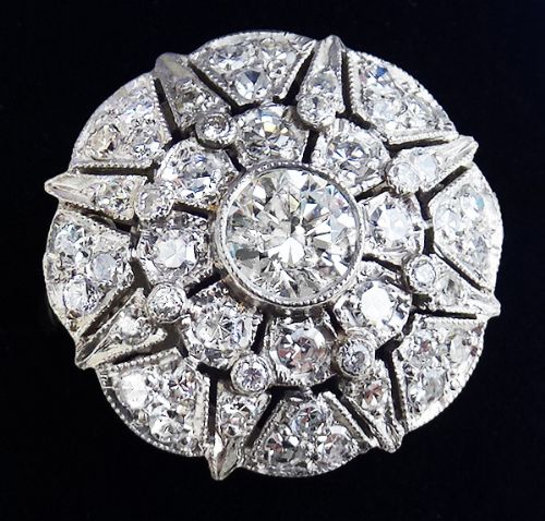 fig 2. An Art Deco platinum cluster ring featuring a circular starburst design set with round diamonds and decorated with fine millegrain edges.