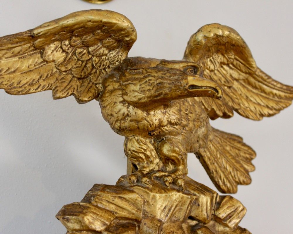A circular giltwood convex mirror topped with a carved eagle finial and decorated with ball ornaments around the frame and foliage at the base. View III