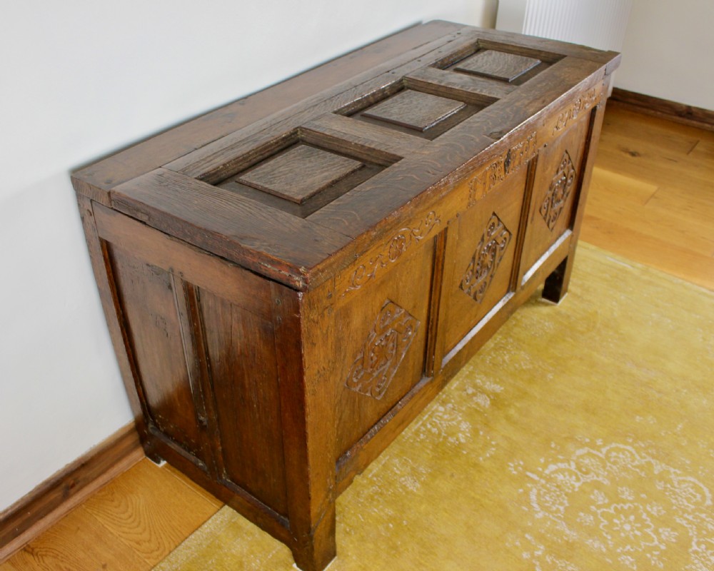 A dark oak coffer featuring three carved front panels with geometric lozenge motifs and a panelled hinged lid. View III