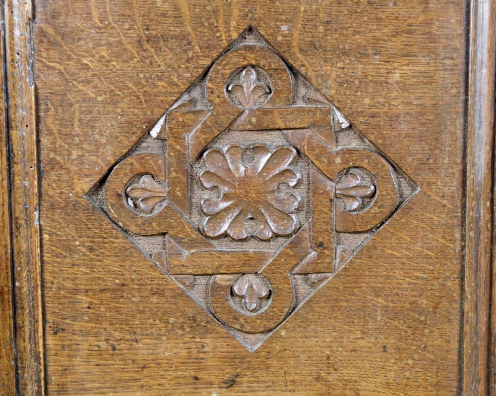 A dark oak coffer featuring three carved front panels with geometric lozenge motifs and a panelled hinged lid. View IV