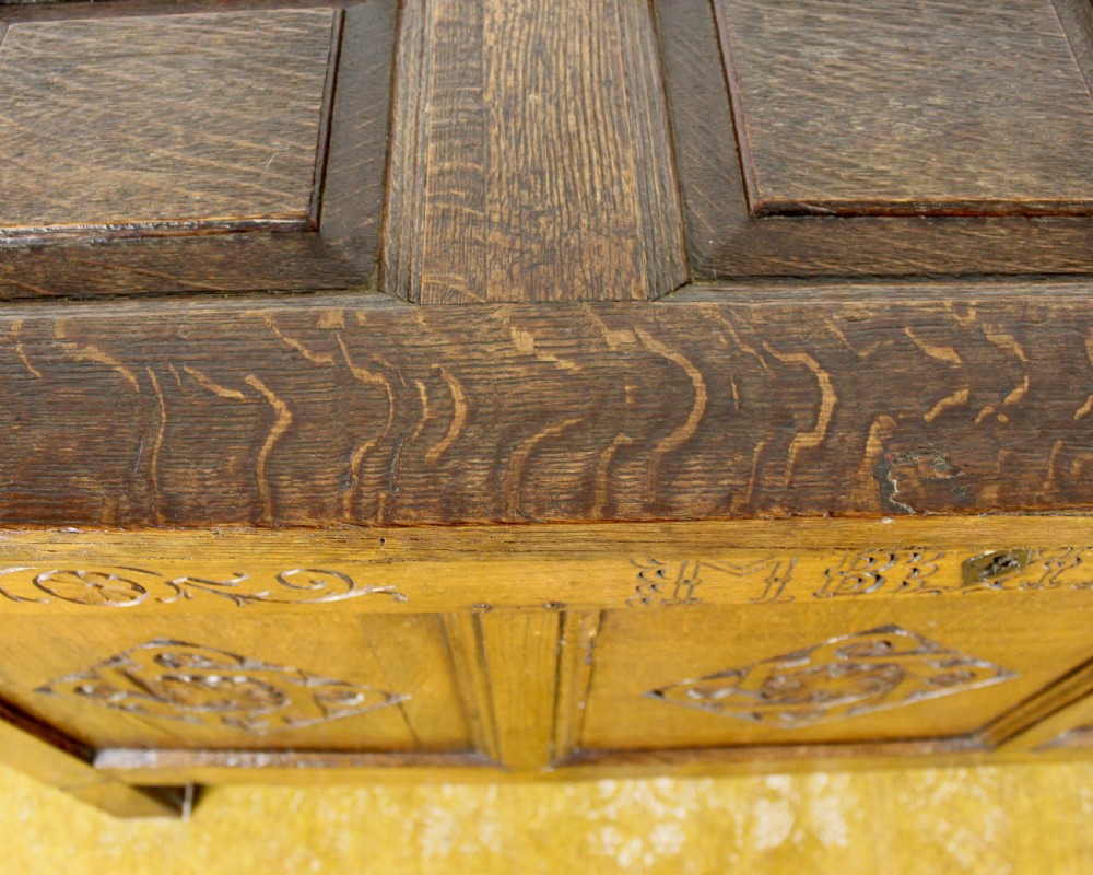 A dark oak coffer featuring three carved front panels with geometric lozenge motifs and a panelled hinged lid. View VII
