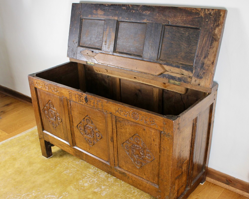 A dark oak coffer featuring three carved front panels with geometric lozenge motifs and a panelled hinged lid. View IX