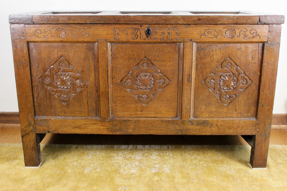 A dark oak coffer featuring three carved front panels with geometric lozenge motifs and a panelled hinged lid. View II