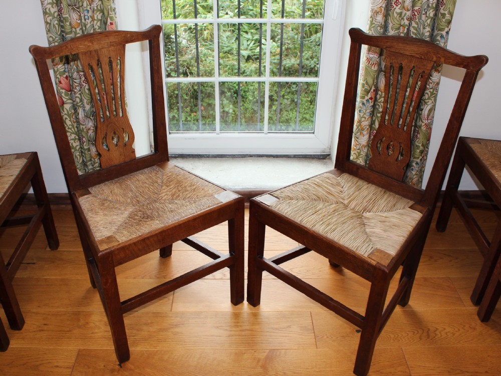 A set of eight George III oak country dining chairs with pierced splat backs and woven rush seats. View IV