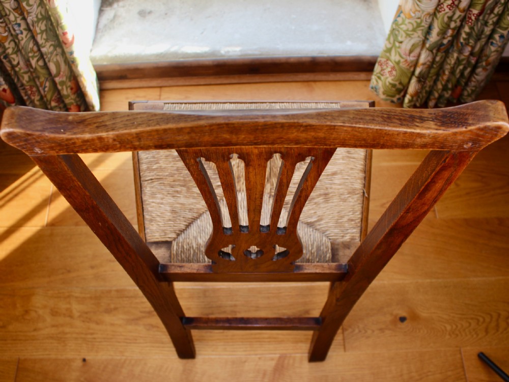 A set of eight George III oak country dining chairs with pierced splat backs and woven rush seats. View VI