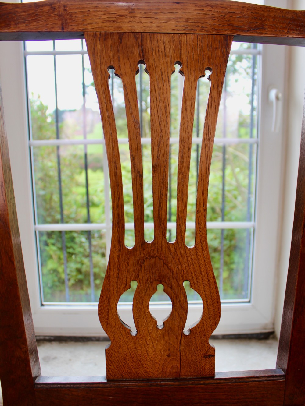 A set of eight George III oak country dining chairs with pierced splat backs and woven rush seats. View VII