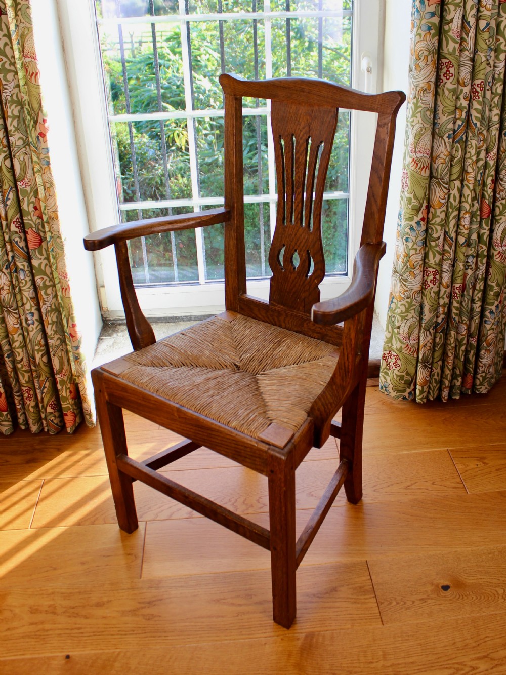 A set of eight George III oak country dining chairs with pierced splat backs and woven rush seats. View X