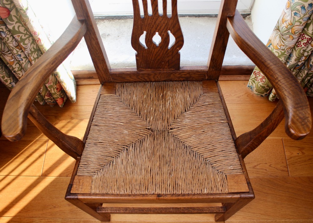 A set of eight George III oak country dining chairs with pierced splat backs and woven rush seats. View XI