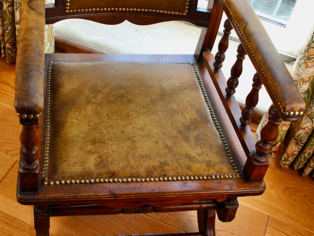 An Edwardian mahogany platform rocking chair with patinated leather upholstery, brass stud detail, and turned spindles. View VIII
