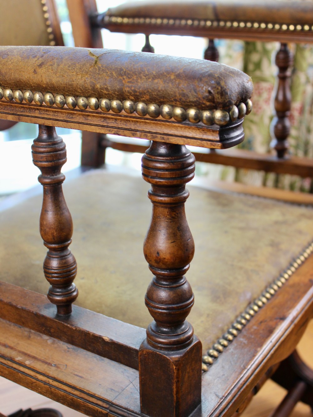An Edwardian mahogany platform rocking chair with patinated leather upholstery, brass stud detail, and turned spindles. View IX