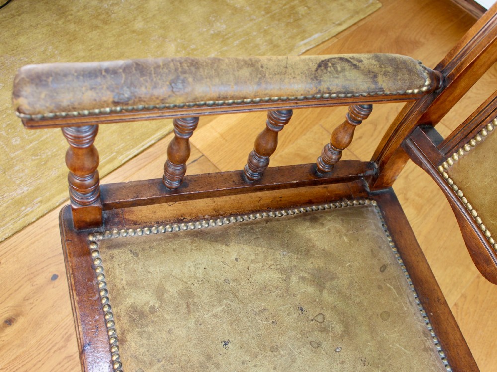 An Edwardian mahogany platform rocking chair with patinated leather upholstery, brass stud detail, and turned spindles. View XI