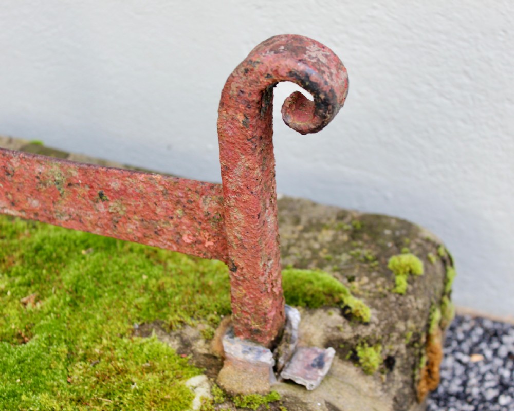 A late Georgian boot scraper featuring a wrought iron blade with scrolled side supports, anchored into a rectangular weathered stone block covered in moss. View III
