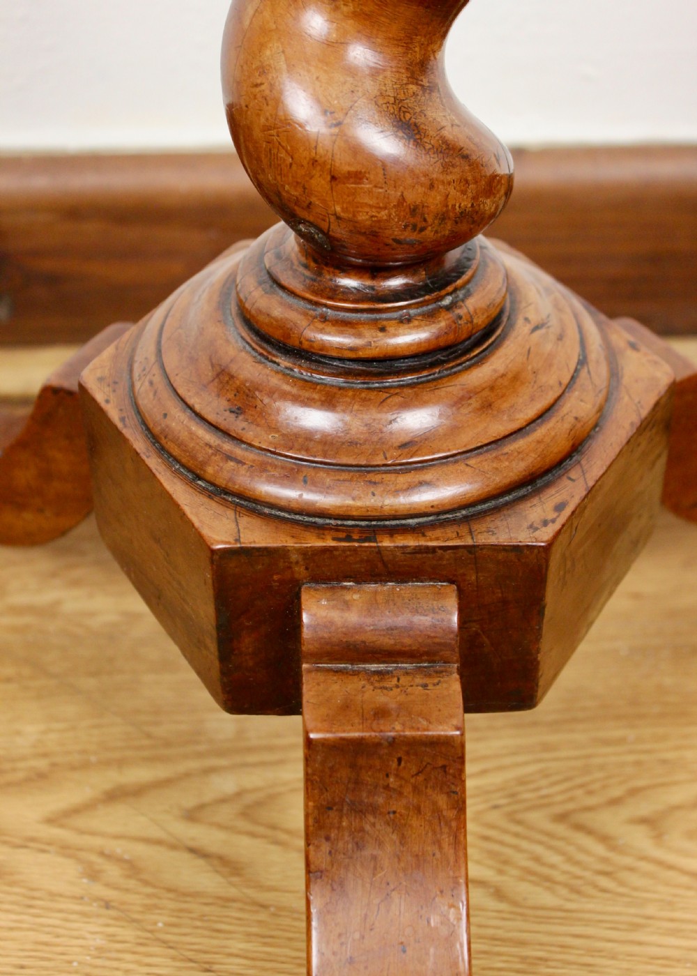 An antique William and Mary walnut candle stand featuring an octagonal top, a central barley-twist column, and a tripod base. View V