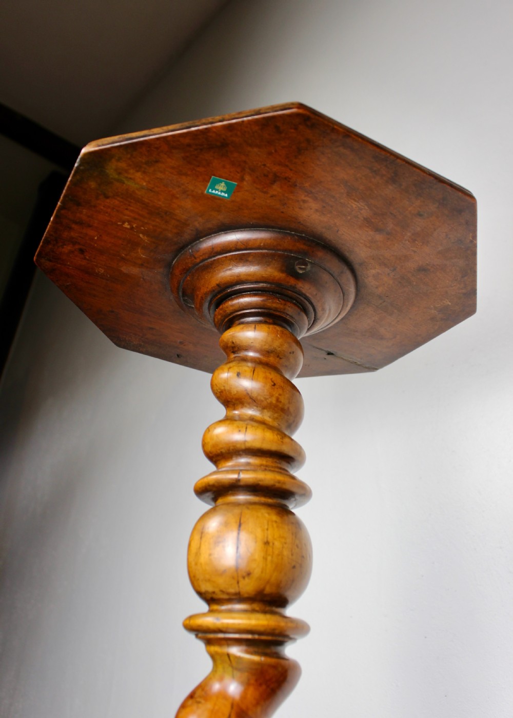 An antique William and Mary walnut candle stand featuring an octagonal top, a central barley-twist column, and a tripod base. View VII