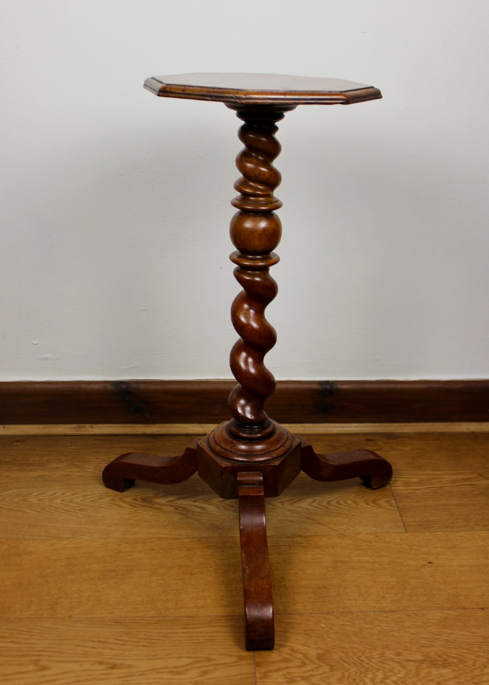 An antique William and Mary walnut candle stand featuring an octagonal top, a central barley-twist column, and a tripod base. View IX