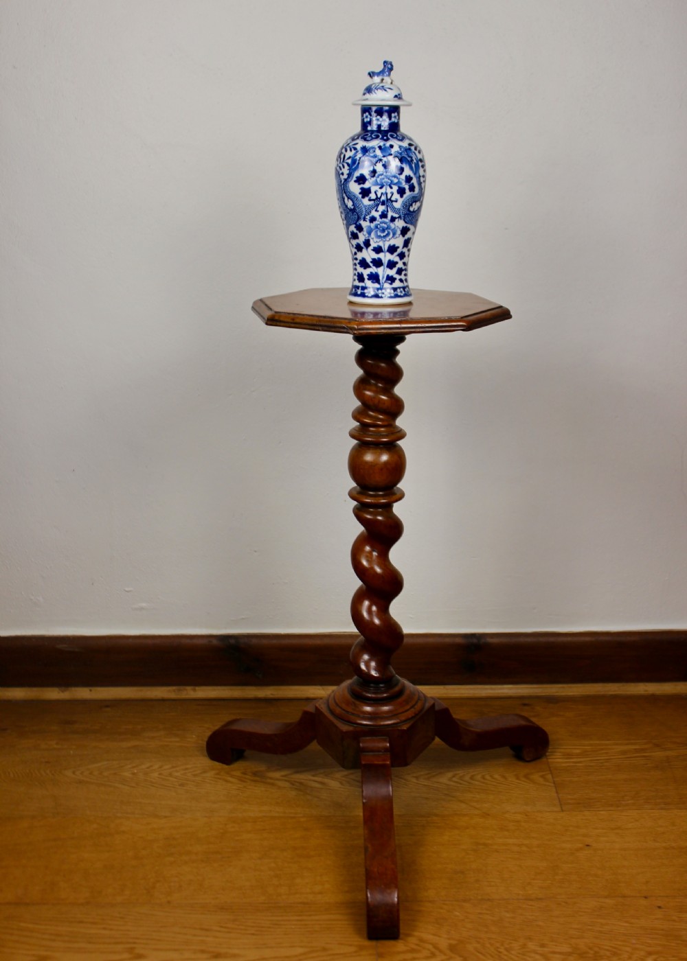 An antique William and Mary walnut candle stand featuring an octagonal top, a central barley-twist column, and a tripod base. View X