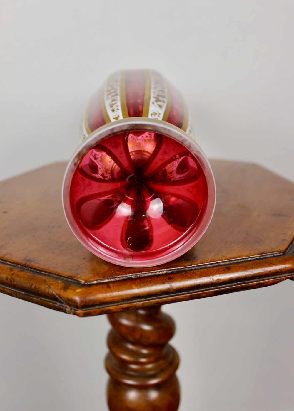 A nineteenth-century Bohemian ruby glass vase featuring white cased glass panels cut to clear with intricate gilt floral ornamentation. View VII