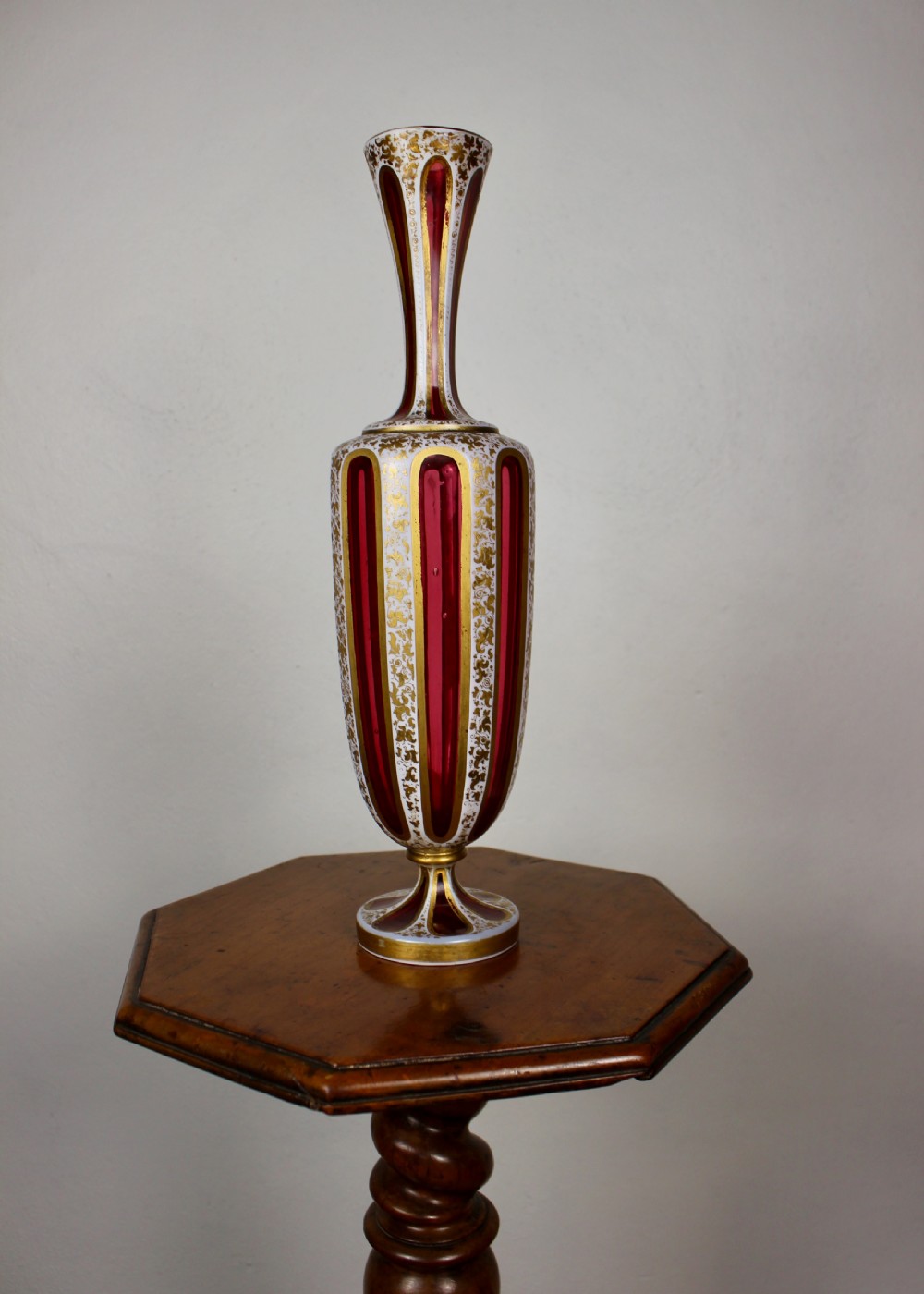 A nineteenth-century Bohemian ruby glass vase featuring white cased glass panels cut to clear with intricate gilt floral ornamentation. View XII