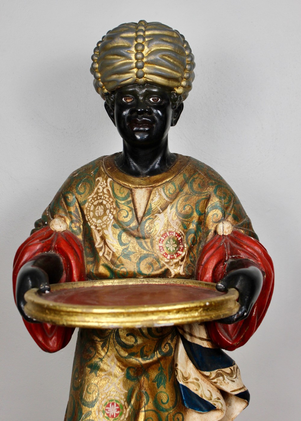 A carved wooden standing Venetian waiter figure wearing a decorated gold tunic and turban while holding a tray on a carved base. View IV