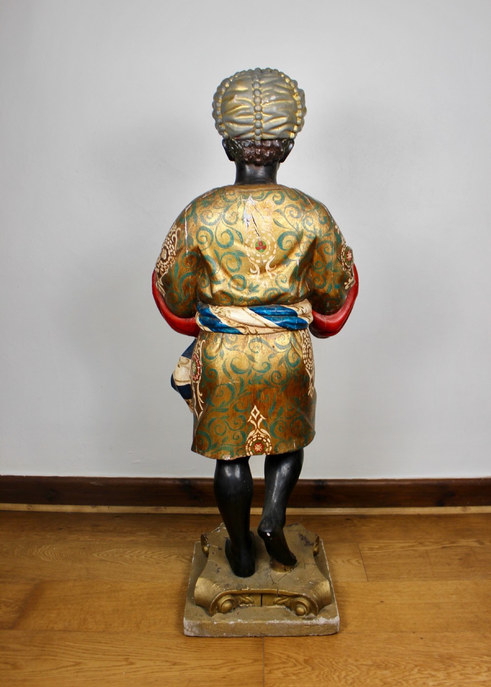 A carved wooden standing Venetian waiter figure wearing a decorated gold tunic and turban while holding a tray on a carved base. View VIII