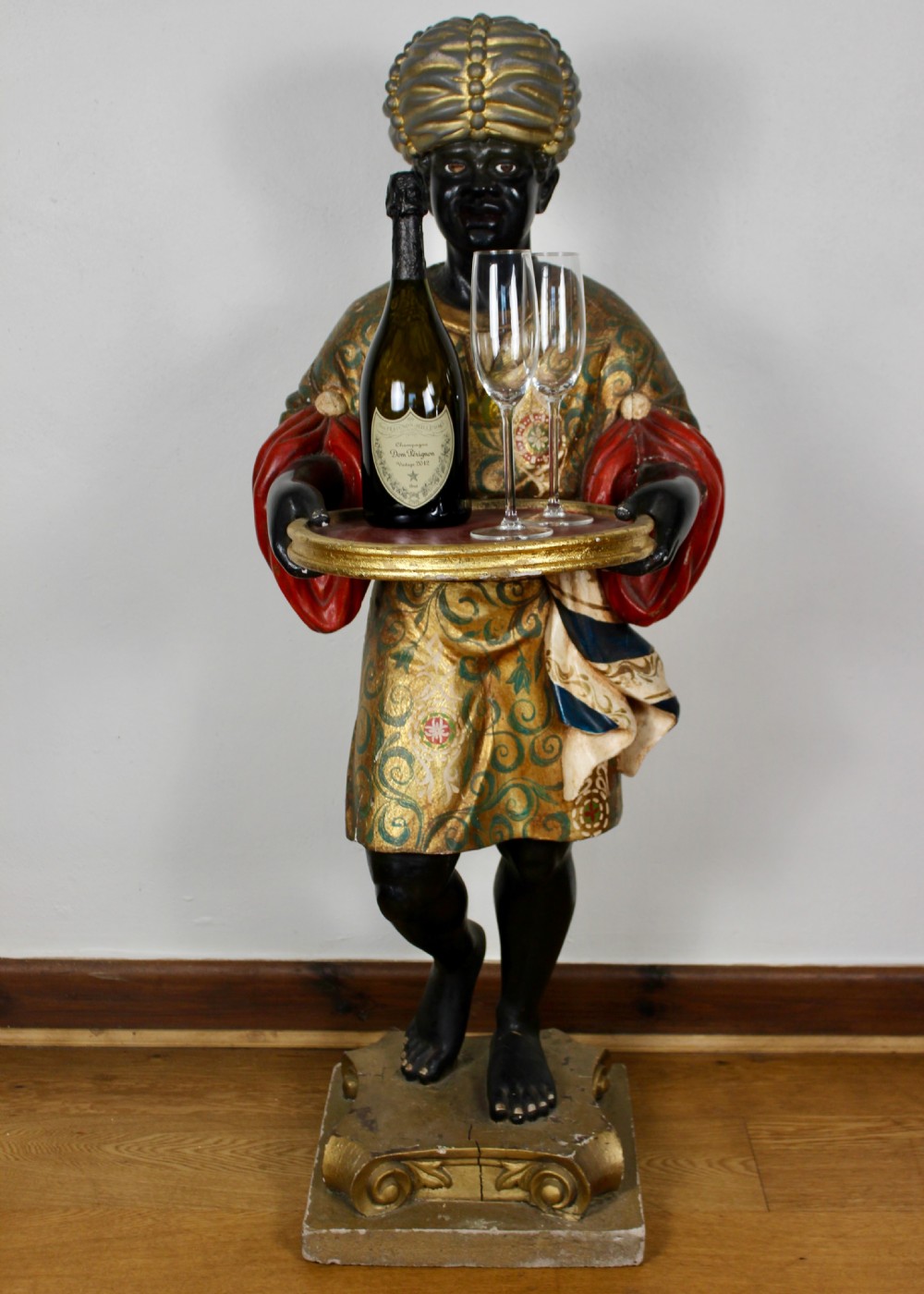 A carved wooden standing Venetian waiter figure wearing a decorated gold tunic and turban while holding a tray on a carved base. View II
