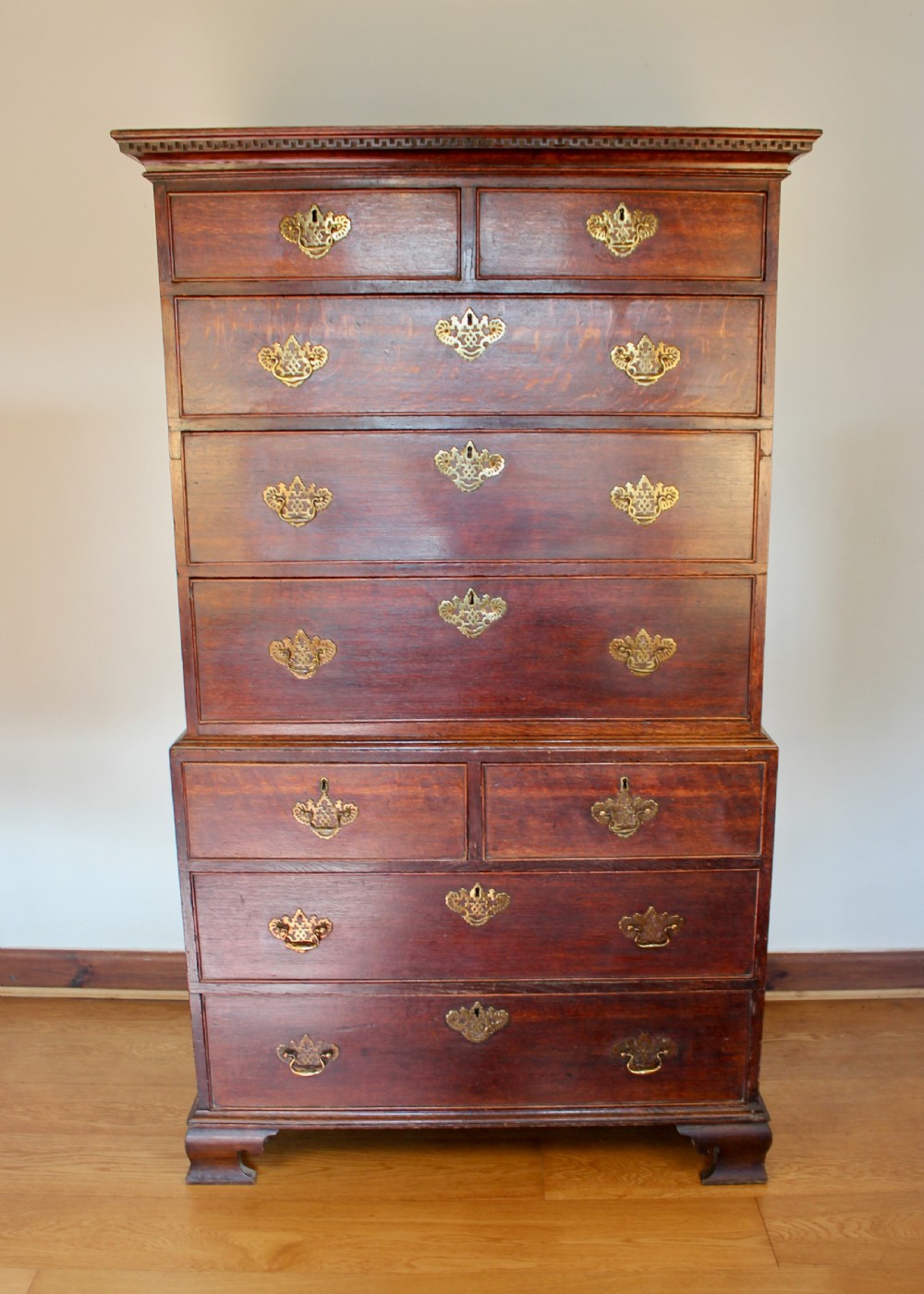 A tall George III dark oak chest-on-chest featuring two short over five long graduated drawers adorned with ornate brass handles and supported on ogee bracket feet. View II